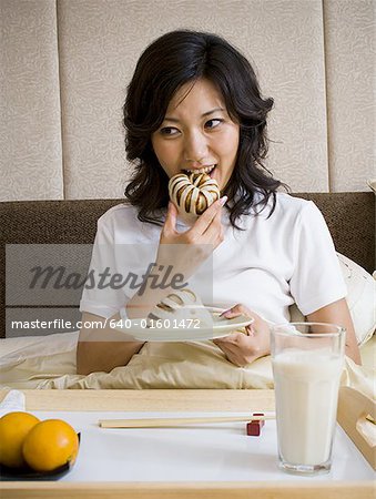 Woman eating breakfast in bed smiling