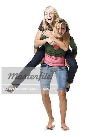 Young girl carrying sister giving piggyback ride Stock Photo