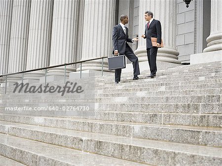 Low angle view of two male lawyers talking on the steps of a courthouse