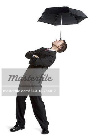 Businessman balancing umbrella on his forehead