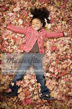 Young girl playing in fallen leaves