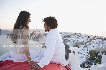 Couple sitting outdoors with champagne flutes and scenic background smiling