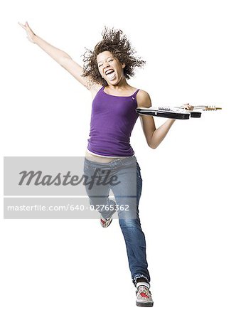 Girl with braces and guitar leaping and sticking tongue out