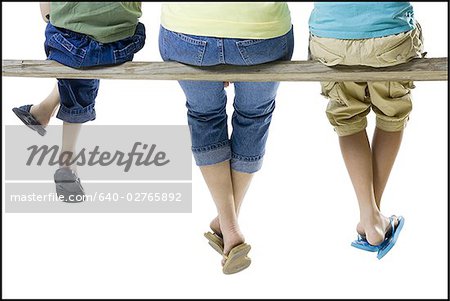 Rear view of a mother and her two children sitting on a wooden plank