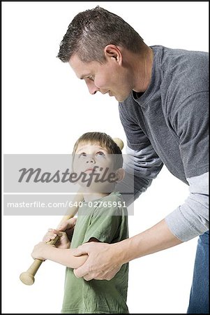 Close-up of father teaching his son how to swing a baseball bat
