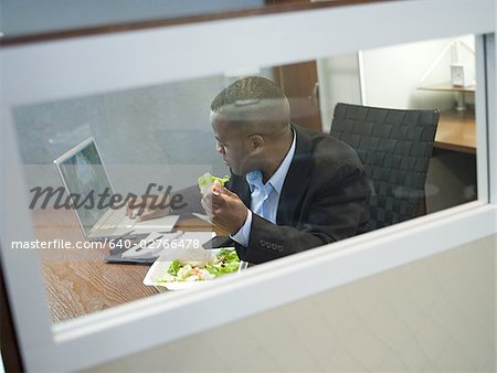 Businessman eating a salad at his desk