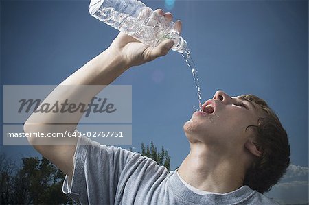 Man drinking water from a bottle at a gym - Stock Photo - Masterfile