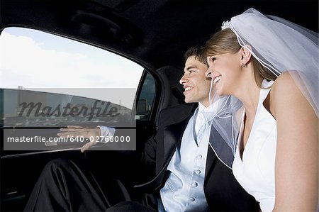 Newlywed couple sitting in a car and smiling