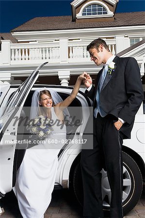 Groom kissing his bride's hand and getting out of a car