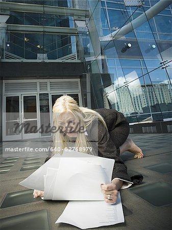 Businesswoman picking paperwork up off the ground