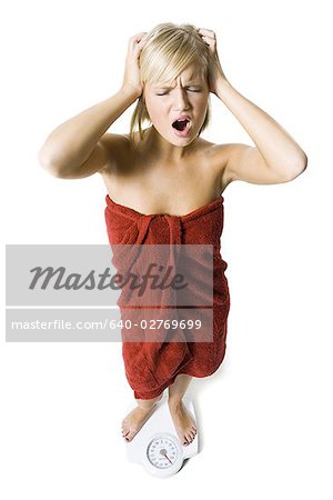 Dieting woman standing on bathroom scale