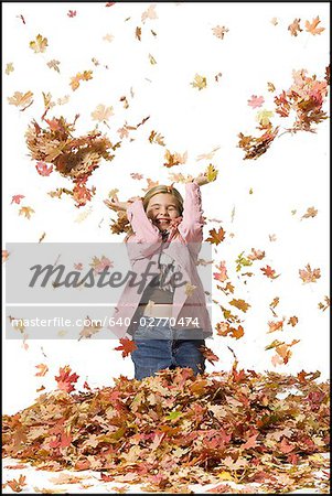 Young girl playing in fallen leaves