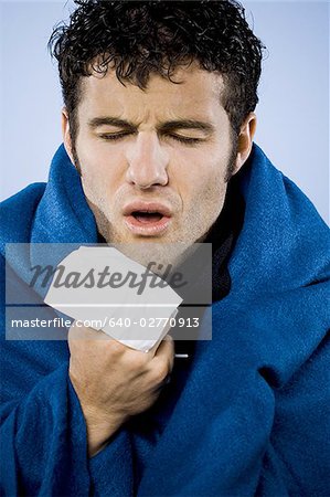 Man wrapped in blanket with tissue