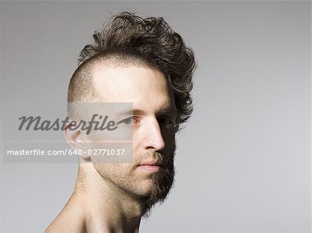 Shirtless man with half shaved hair and beard