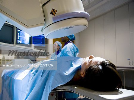 Woman on diagnostic bed with male and female technicians looking at monitors