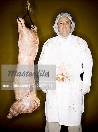 Butcher with hanging carcass and knife smiling