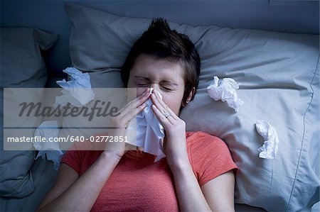 Woman lying in bed with tissues
