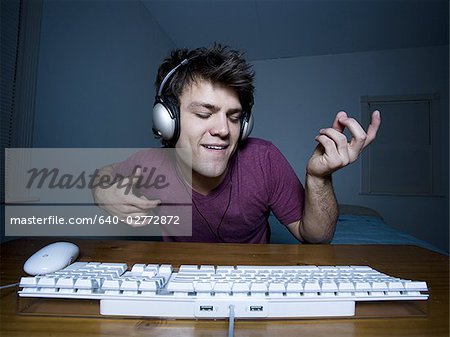 Man with keyboard and headphones playing air guitar