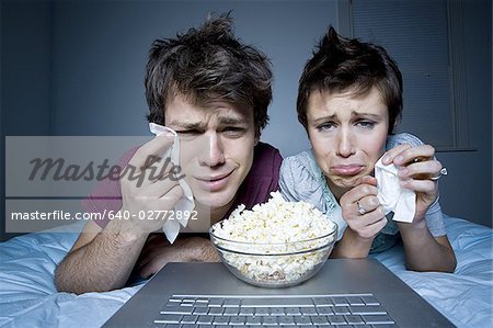 Couple crying with tissue and bowl of popcorn