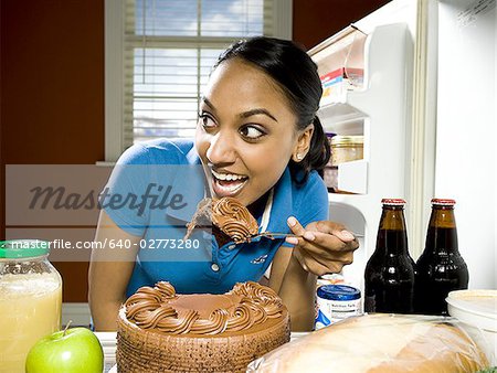 Woman devouring chocolate cake from refrigerator