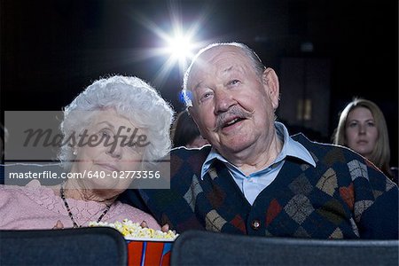 Man and woman watching film at movie theater smiling