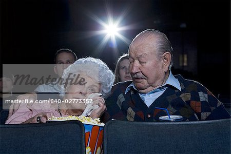 Man and woman watching movie in theater crying with popcorn