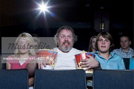 640-02773422em-large-man-with-buckets-of-popcorn-and-drink-at-movie-theater-between.jpg