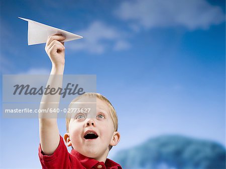 Boy with paper airplane outdoors