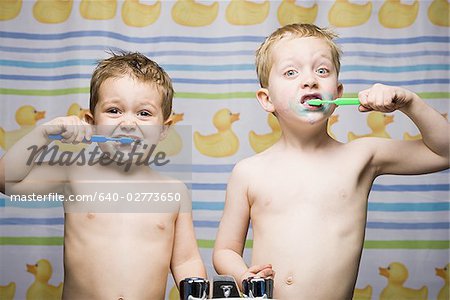 Two boys brushing teeth in bathroom sink