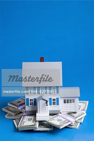 Toy house on pile of one hundred dollar bills