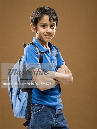 Boy standing with arms crossed and backpack smiling