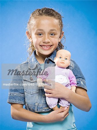 Girl holding baby doll smiling