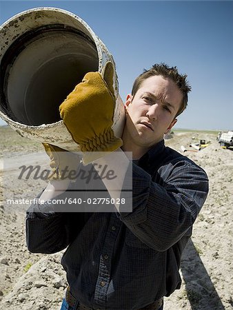 Man carrying pipe outdoors smiling