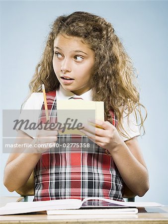Girl sitting at desk with workbook reading note