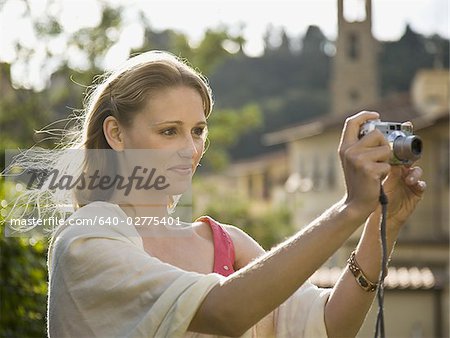 Woman smiling and taking a photograph outdoors
