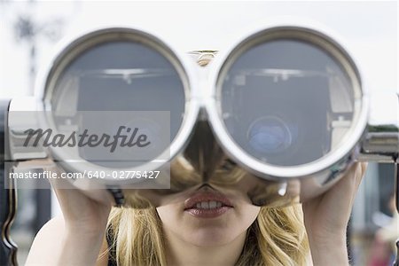 Woman looking through coin operated binoculars smiling