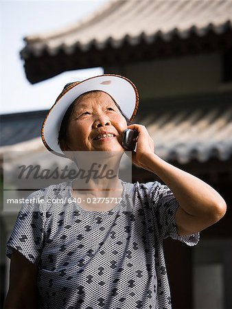 Woman with sun visor outdoors smiling talking on cell phone