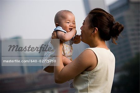 Woman holding baby outdoors smiling