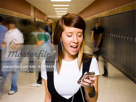 High School girl at school listening to MP3 player.