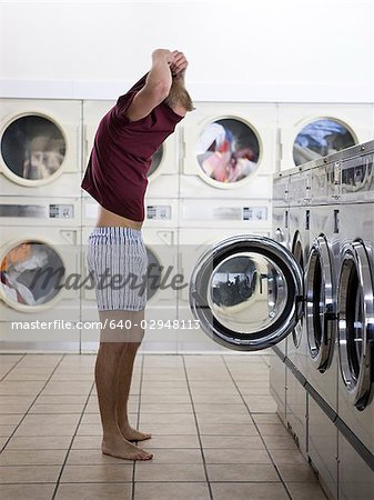 man taking off his clothes at a laundromat