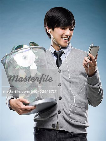 man with a trash can full of cd's and holding an iPod