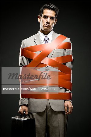 businessman wrapped up with red tape