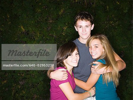 teenage boy and two teenage girls hugging