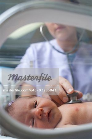 Nurse examining newborn in incubator