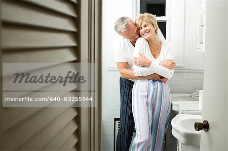 Mature couple in bathroom hugging