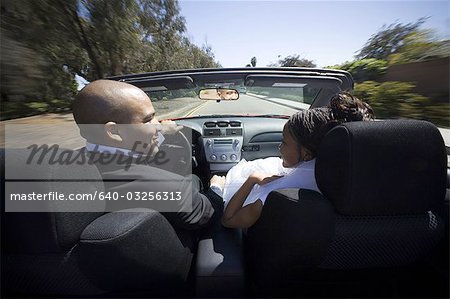 Rear view of a newlywed couple looking at each other in a car