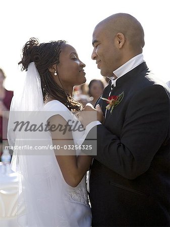 Profile of a newlywed couple holding hands and looking at each other