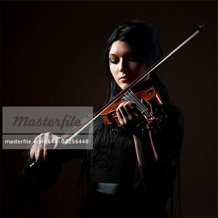 Young woman playing violin, studio shot