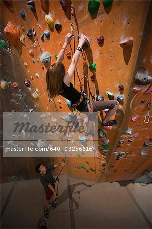 USA, Utah, Sandy, boy (12-13) assisting teenage girl (14-15) on indoor climbing wall