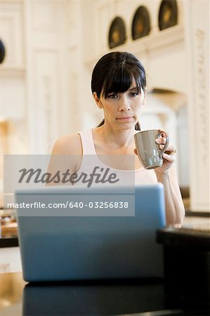 USA, Utah, Alpine, mid adult woman sitting behind laptop and holding mug